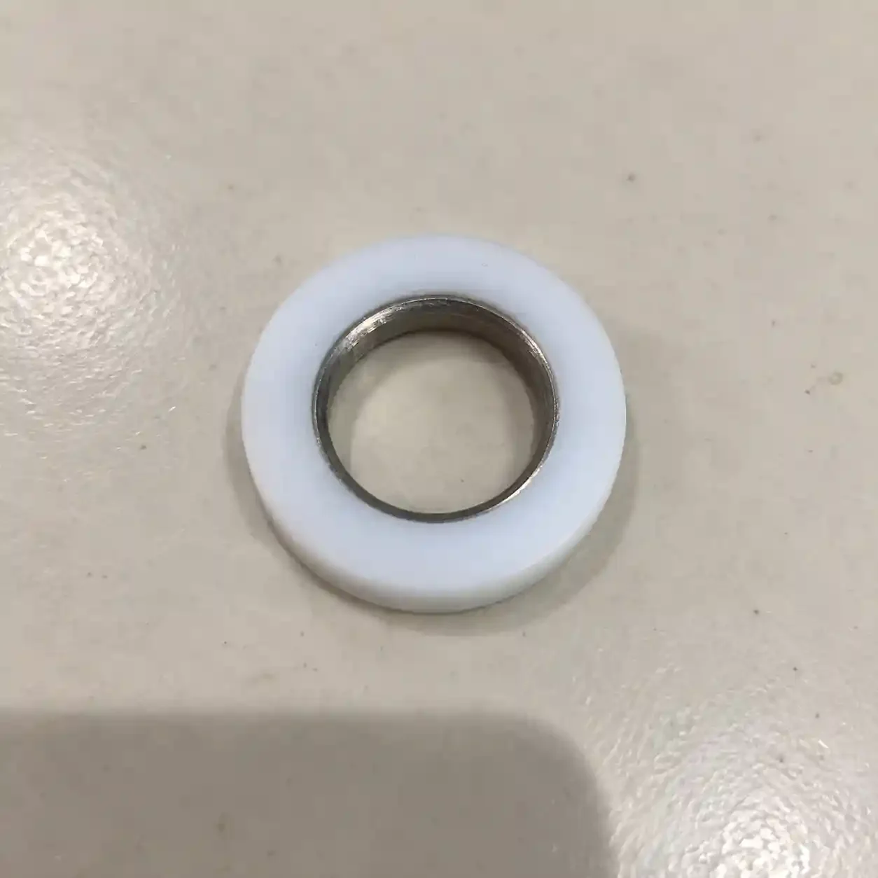 Witte kunststof ring met een opstaande metalen inzet in de opening