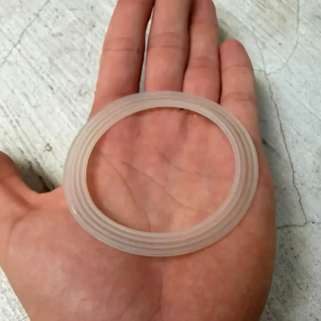 Doorschijnende ring met meerdere concentrische ribbels op een hand